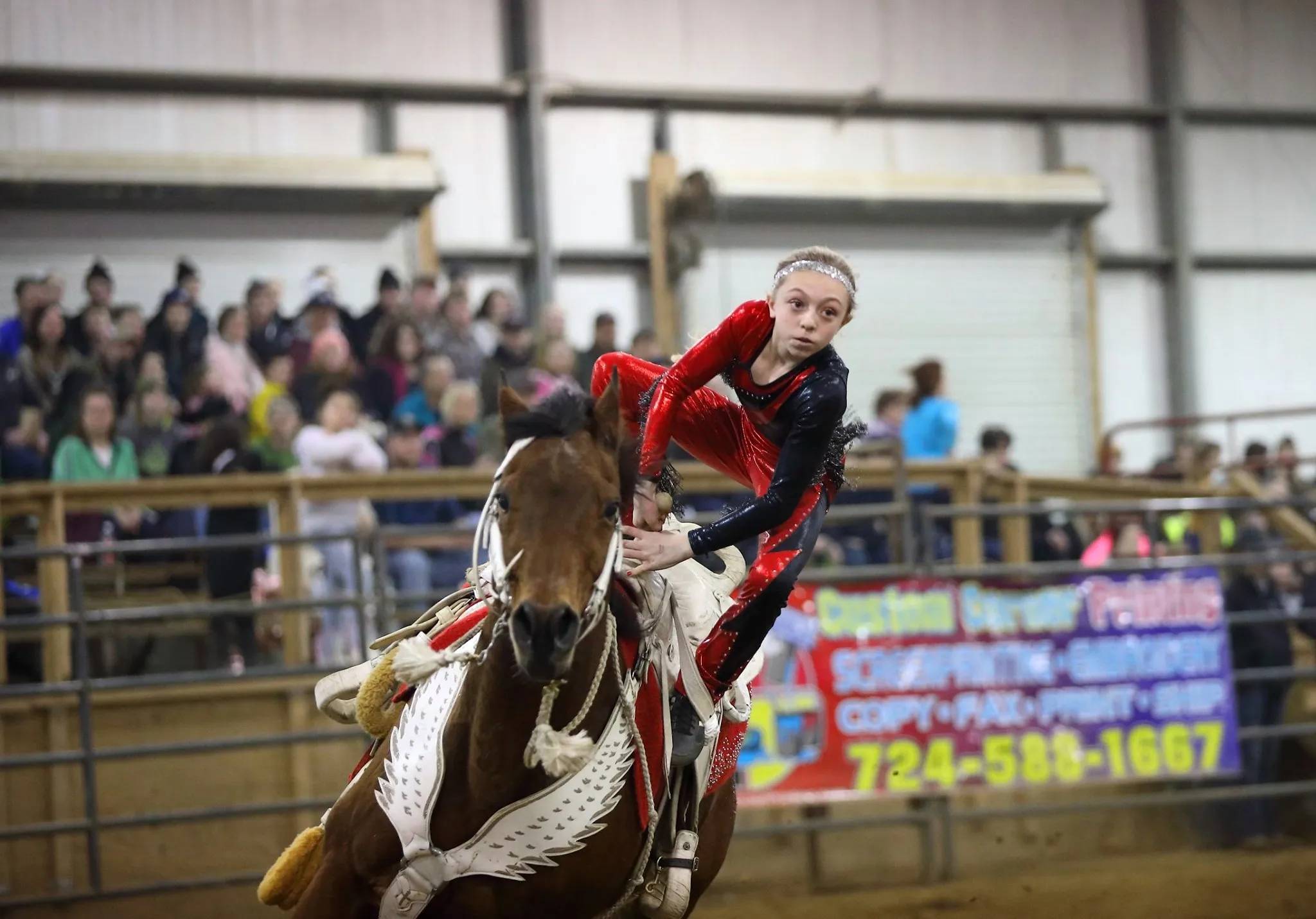 Young Girl Performing Trick Riding on Horse in Arena
