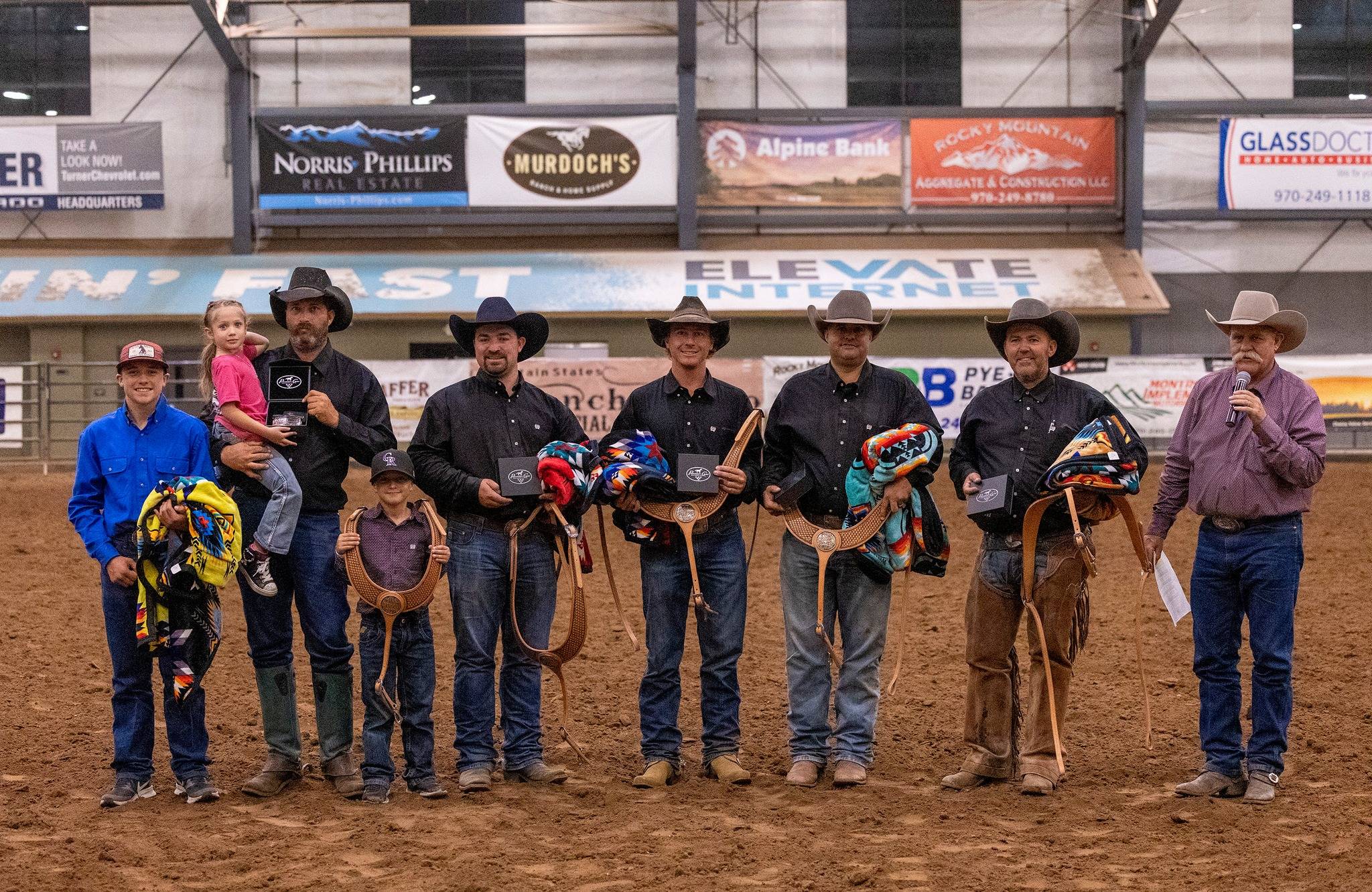 Group of Cowboys and Children Receiving Awards at an Indoor Rodeo Event