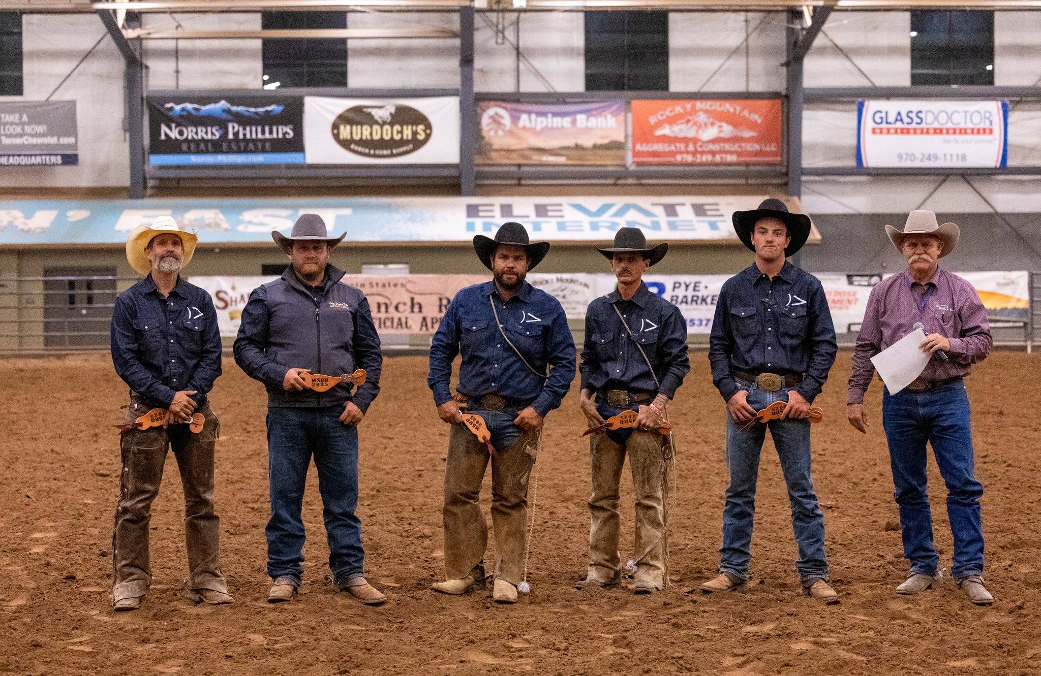 Group of Cowboys and Officials in an Indoor Rodeo Arena